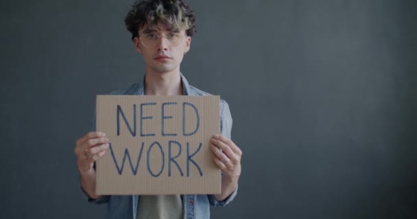 仕事のサインは灰色の色の背景に立ってキャリアの機会を検索する必要がある保持している失業者のスローモーションの肖像画 失業と若者の概念 — ストック動画