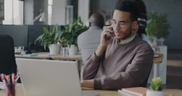 Ofis Çalışanı Afro Amerikan Adam Cep Telefonuyla Görüşmeleri Yapıyor Dizüstü — Stok video