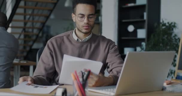 深刻なアフリカ系アメリカ人の男性のオフィスの労働者は デスクで書類を見て企業文書を読む 業務及び財務書類の概念 — ストック動画