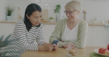 Gönüllü olarak yaşlı bir kadına akıllı telefonu ekranlara dokunmayı ve mutfakta konuşmayı öğretiyor. Modern teknoloji ve emeklilik kavramı.