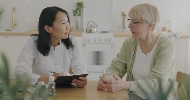 Dokter Wanita Berbicara Dengan Wanita Tua Pasien Yang Membahas Catatan — Stok Video