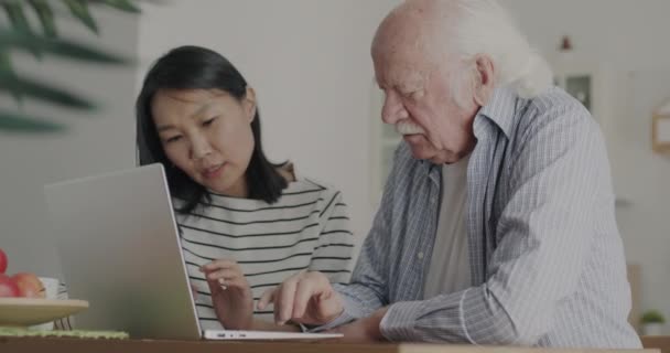 Young Woman Teaching Elderly Man Pensioner Using Laptop Together Kitchen — Stock Video