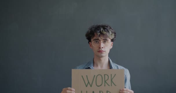 Portret Poważnego Młodzieńca Trzymającego Work Hard Szarym Tle Ciężko Pracujący — Wideo stockowe