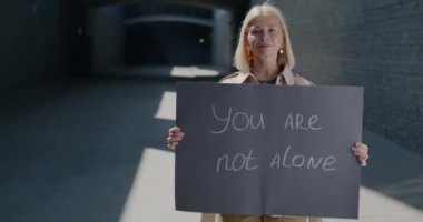 Olgun bir kadının ağır çekimde elinde tuttuğu portre tuğla duvar arkasında dayanışmayı ifade eden bir tek sen değilsin. İnsanlar ve destek kavramı.