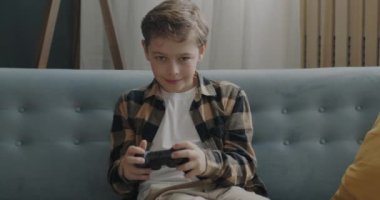 Oyun oynayan mutlu bir çocuğun portresi joystick kazanarak evde kameraya bakarken eğleniyor. Oyun ve çocukluk kavramı.