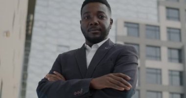Sakin ve kendinden emin Afro-Amerikan iş adamının sakin portresi. Kolları şehirli arka planında çapraz duruyor. İnsanlar ve özgüven ifadesi kavramı.