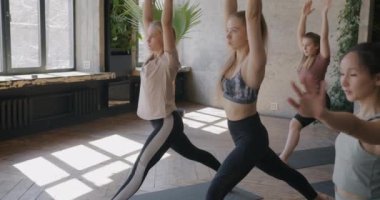 Yoga stüdyosunda spor yapan Asya 'lı ve Kafkas kökenli genç kadınların birlikte antrenman yapmaları. İnsanlar ve sağlıklı yaşam tarzı kavramı.
