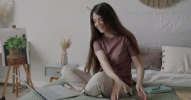 İnternetten video görüşmesi yapan neşeli genç bir kadın grafik tablet ekranında resim göstererek evde oturup resimle ilgili tartışmalar yapıyor.