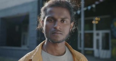 Güneşli bir yaz gününde şehrin dışında gülümseyen Hintli genç adamın yavaş çekim portresi. İnsani duygular ve neşeli insanlar kavramı.