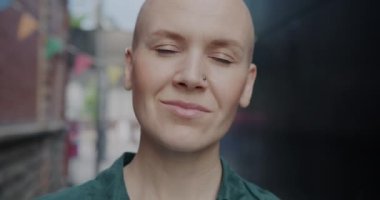 Yazın açık havada durup şehir hayatının tadını çıkarırken gülümseyen yaratıcı kızın yakın çekim yavaş portresi. Mutluluk ve şehir yaşam tarzı konsepti.