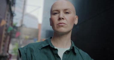 Ciddi bir kadının dışarıda kameraya bakıp gülümsemesinin yavaş çekim portresi. Pozitif duygu ve modern gençlik kavramı.