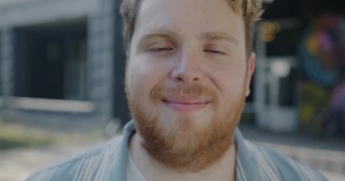 Yaz günü kameraya bakarak gülümseyen neşeli öğrencinin yavaş çekim portresi. Tasasız gençler ve duygu konsepti.