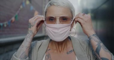 Covid-19 salgını sırasında yüz maskesi takan zarif genç bir kadının yavaş çekim portresi. Sağlık ve koronavirüs konsepti.