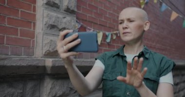 Kentin dışındaki akıllı telefondan kendine güvenen genç bir kadın online video görüşmesi yapıyor. İletişim ve modern kablosuz teknoloji kavramı.