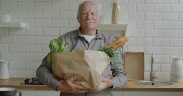 Portrett Pensjonert Mann Med Papirpose Som Holder Dagligvarer Stående Kjøkkenet – stockvideo
