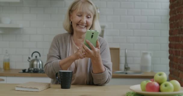 Elderly Lady Swiping Smartphone Screen Enjoying Social Media Content Drinking — Stock Video