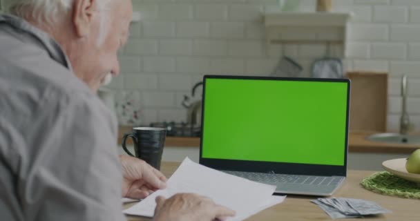 从肩膀上看去 老人正在付账 一边看报纸 一边看彩色键绿色屏幕笔记本电脑和桌上的现金 财务和文书工作概念 — 图库视频影像