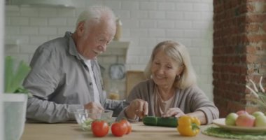 Kıdemli kadın salata pişiriyor ve yaşlı bir adamla konuşuyor. Mutfakta baş parmağını kaldırıyor. Sağlıklı beslenme ve aile yaşam tarzı konsepti.