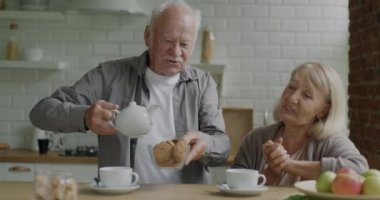 Kıdemli karı koca evde çay ve kurabiye hazırlıyor ve mutfakta öğle yemeğinin tadını çıkarıyor. Aile hayatı ve lezzetli yemek konsepti..