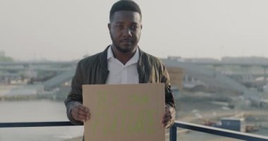 Afrika kökenli Amerikalı bir adamın elinde ağır çekimde çekilmiş bir portresi, şehrin arka planında duran gelecek afişimiz olacak. Halk ve sosyal aktivizm kavramı.