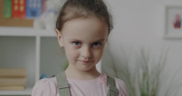 Медленный Портрет Счастливой Маленькой Девочки Показывающей Жест Улыбающейся Стоя Помещении — стоковое видео