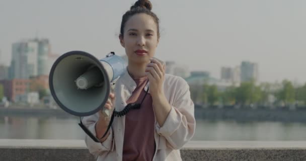 屋外でスピーカーを保持し カメラを見て立って若い女性の平和的な抗議者のスローモーション 社会活動とフェミニズムの概念 — ストック動画