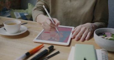 Yaratıcı illüstratör grafik tableti kullanarak resim çiziyor ve kulaklıkla müzik dinliyor. Milenyum ve modern aletler konsepti.