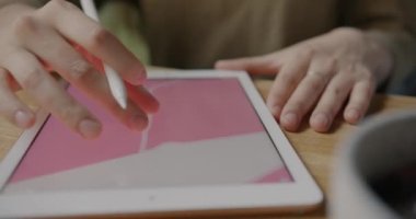 Stylus 'un kafedeki masada çalışan dijital grafik tableti ile soyut bir resim oluşturmasıyla yakın plan. Yaratıcı işgal ve teknoloji kavramı.