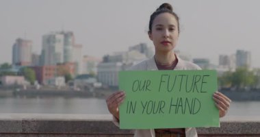 Şehrimizdeki barışçıl protesto sırasında geleceğimizi tutan melez kadının yavaş çekimde portresi senin el ilanında. Eylemcilik ve küresel değişim kavramı.
