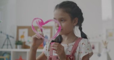 Dairedeki pencereye pembe kalp çizen sevecen çocuk yavaş hareket ediyor. Güzel küçük kız sanatla ilgilenen yaratıcı aktivitelerden zevk alıyor..