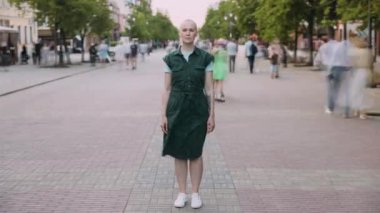 Kalabalık bir caddede şehir merkezinde duran çekici, modern bir kadının hızlandırılmış portresi. Kentsel yaşam tarzı ve yaz aylarında metropol kavramı.