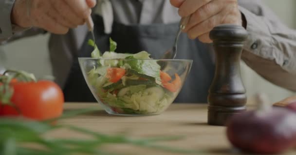 野菜を混ぜる男性の手のクローズアップは 家庭でのサラダ調理ディナーに塩を追加します 健康的な栄養と料理のレシピコンセプト — ストック動画