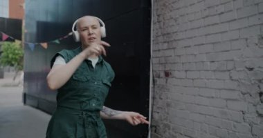 Neşeli bir kadın dans ediyor ve şarkı söylüyor modern şehir sokaklarında kablosuz kulaklık takarak eğleniyor. İnsanlar ve eğlence etkinliği konsepti.