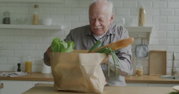 Senior Man Packa Upp Papperspåse Tittar Livsmedel Grönsaker Och Bröd — Stockvideo
