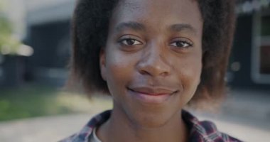 Sıcak bir yaz gününde dışarıda kameraya bakarken gülümseyen sakin genç bayanın yakın plan portresi. İnsani duygular ve gençlik kavramı.