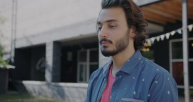 Neşeli Orta Doğulu esmerin portresi mutlu bir yüzle kameraya dönüyor ve şehirde el sallıyor. Hoşgeldiniz ve merhaba konsepti.