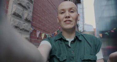 Dost canlısı genç bir kadının el sallayarak gülüşen bir portresi açık havada online video görüşmesi yapıyor. İletişim ve gençlik kavramı.