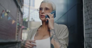 Şehrin dışında dikilen neşeli bir bayanın portresi ve cep telefonuyla gülüp eğlenen sohbetler. İnsanlar ve iletişim konsepti.