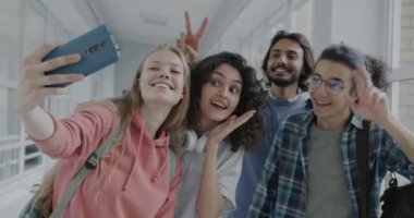 Üniversitede eğlenirken selfie çeken neşeli erkek ve kadınların yavaş çekimleri. Eğitim ve arkadaşlık kavramı.