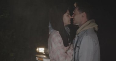 Sevgi dolu bir çiftin birbirine sarılıp gece açık havada araba farlarıyla aydınlatılmış aşklarını dile getirmesi. İlişki ve yolculuk kavramı.