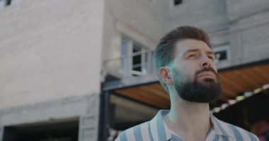 Düşünceli genç adamın yavaş hareket eden portresi yazın açık havada manzaranın tadını çıkarıyor. Halk ve şehir hayatı kavramı.