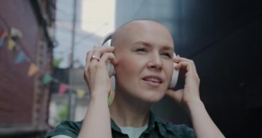 Kulaklık takan, müzik dinleyen ve sokakta dans eden genç bir kadının yavaş çekim portresi. Gençlik ve kültür kavramı.