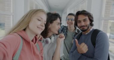 Kameraya poz veren neşeli öğrencilerin portresi. Lise lobisinde selfie çekerken eğleniyorlar. Fotoğraf ve mutlu gençler konsepti.