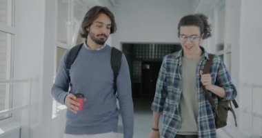 Üniversite koridorunda elinde kahve ve sırt çantası olan iki adamın Dolly 'nin fotoğrafı. Modern yaşam tarzı ve iletişim konsepti.