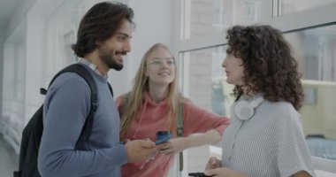 Kaygısız gençler kampüste konuşurken gülüyorlar ve akıllı telefonlar kullanıyorlar. Modern teknoloji ve gençlik yaşam tarzı kavramı.