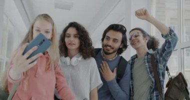 Bir grup erkek ve kız öğrenci online video görüşmesi yapıyorlar. Akıllı telefonlar konuşuyorlar ve üniversite koridorunda el sallıyorlar. Gençlik ve iletişim kavramı.
