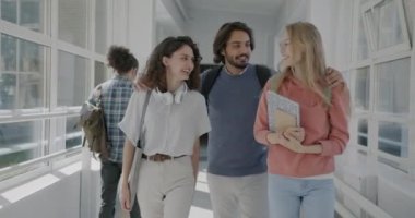 Tasasız öğrencilerin kolejde çeşitli gruplar halinde yürümeleri gülüşmeleri, konuşmaları ve eğlenmeleri. Gençlik ve eğitim kavramı.