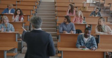 Deneyimli bir profesör sınıfta soruları cevaplayan bir grup öğrenciyle konuşuyor. Akademik eğitim ve mesleki sohbet kavramı.