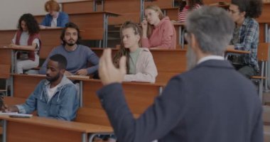 Çeşitli öğrenci grupları ders verirken profesörün sınıfta soru sormasını dinliyor. Modern eğitim ve mesleki işgal kavramı.