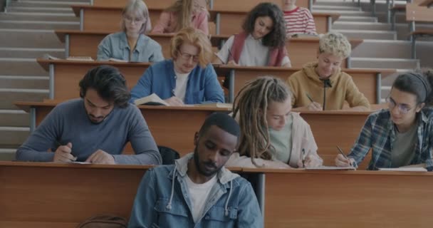 多种族的学生 女孩和编写考试的男孩都集中在学校的课桌前 青年和教育中心概念 — 图库视频影像